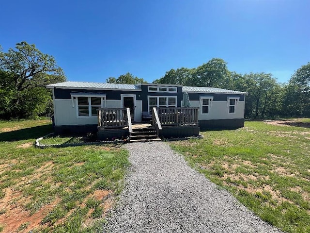 view of front of home featuring a front lawn, a deck, and metal roof