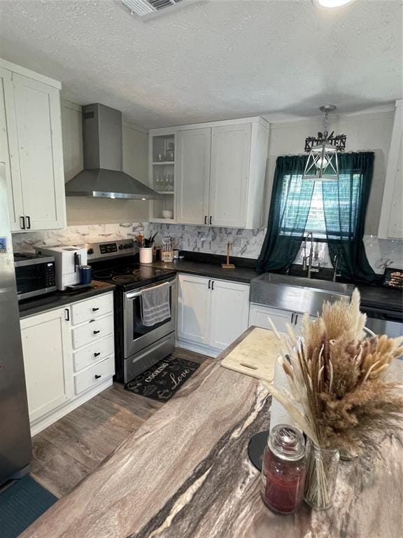 kitchen with dark countertops, decorative backsplash, appliances with stainless steel finishes, and wall chimney range hood