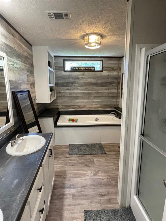 full bath with visible vents, wood walls, wood finished floors, and a shower stall