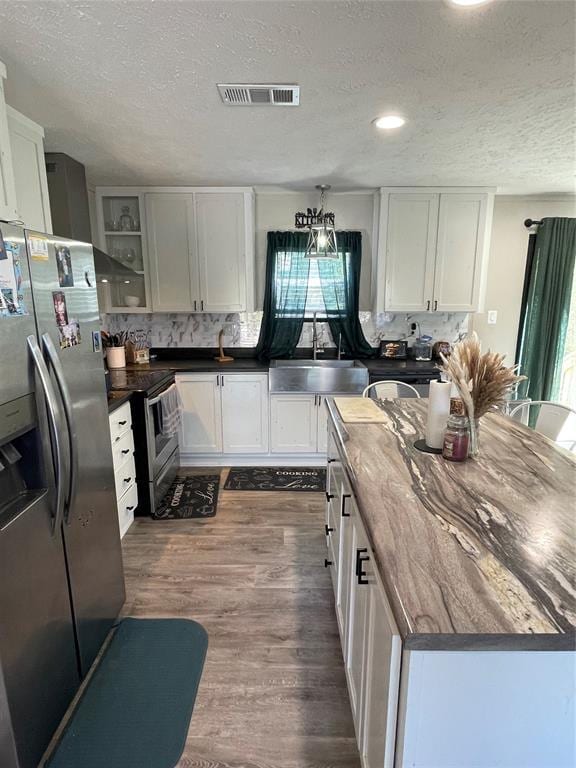 kitchen with a textured ceiling, visible vents, a sink, stainless steel appliances, and dark wood-type flooring