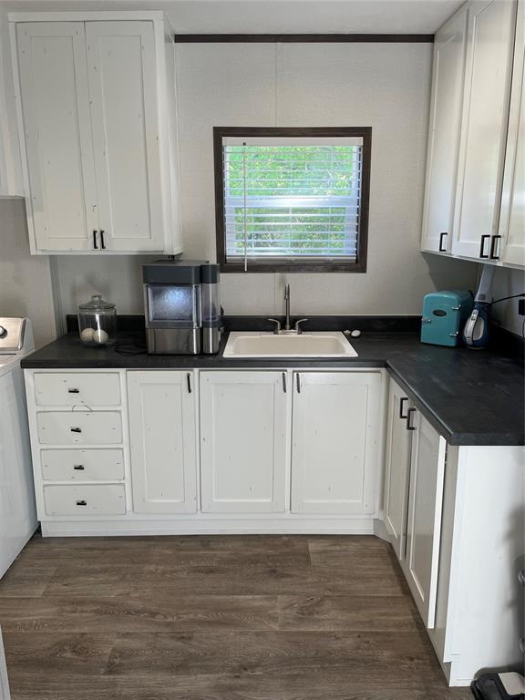 kitchen featuring a sink, white cabinets, and dark countertops