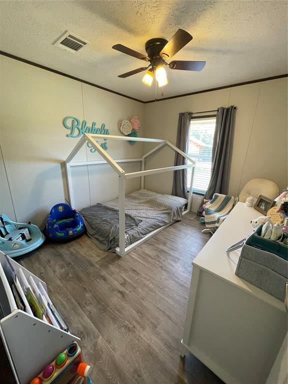 bedroom with wood finished floors, a textured ceiling, and visible vents