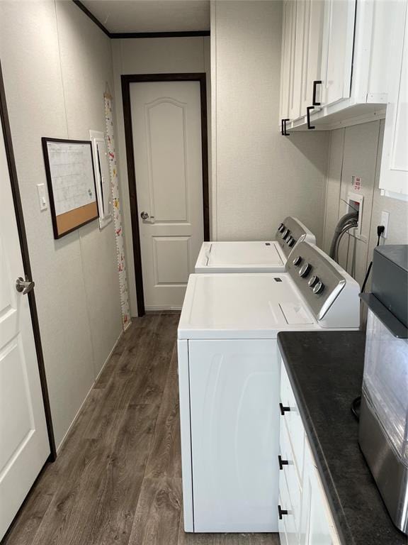 clothes washing area with cabinet space, dark wood-style flooring, and washing machine and clothes dryer