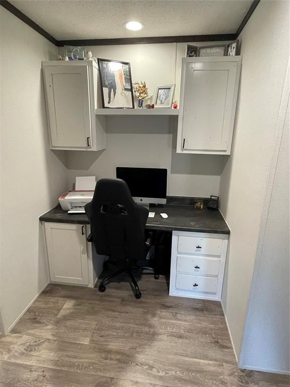 home office with built in study area, a textured ceiling, and wood finished floors