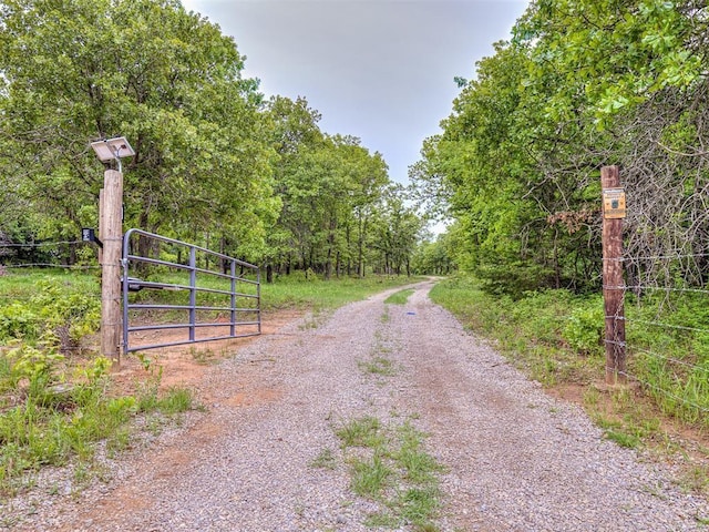 view of road featuring a forest view and a gate