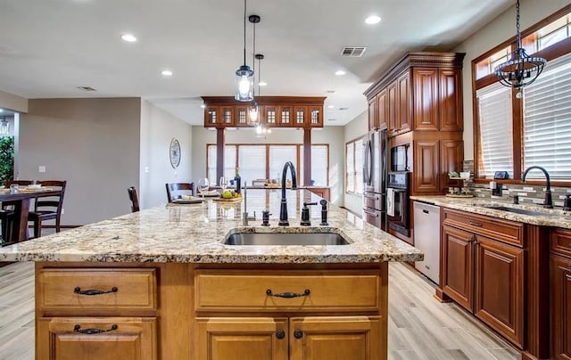 kitchen featuring a sink, appliances with stainless steel finishes, an island with sink, and visible vents