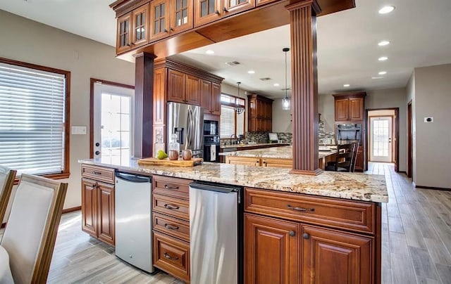 kitchen featuring ornate columns, stainless steel appliances, light wood-style floors, a kitchen island, and visible vents