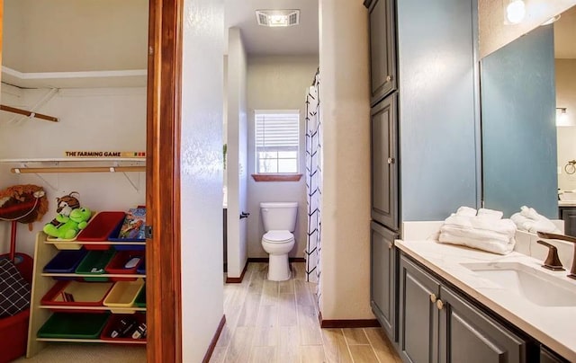 bathroom with visible vents, baseboards, toilet, wood finished floors, and vanity