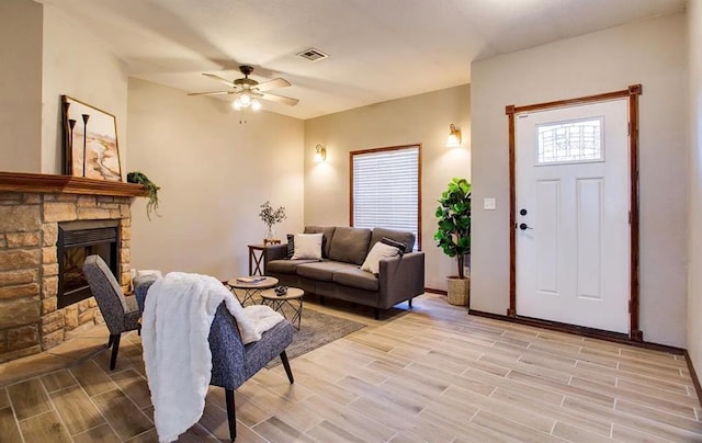 living room with a fireplace, light wood-style floors, ceiling fan, visible vents, and baseboards