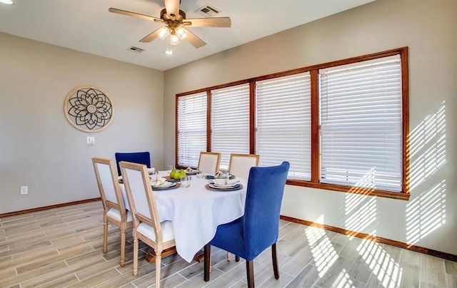 dining space with visible vents, a ceiling fan, light wood finished floors, and baseboards