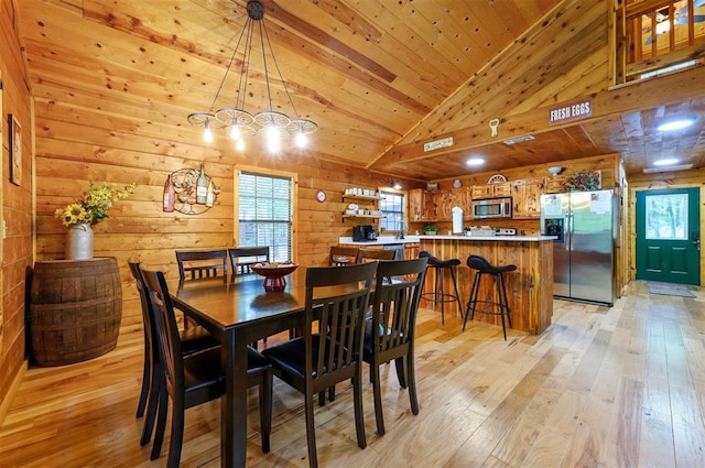 dining area featuring wooden walls, light wood-style floors, lofted ceiling, and wooden ceiling