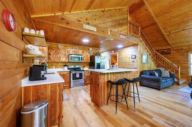 kitchen with appliances with stainless steel finishes, a sink, wood walls, wood ceiling, and light wood-style flooring