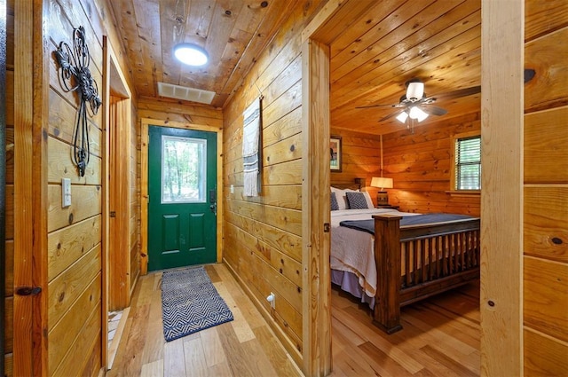 entryway featuring light wood-style floors, wooden ceiling, wood walls, and ceiling fan