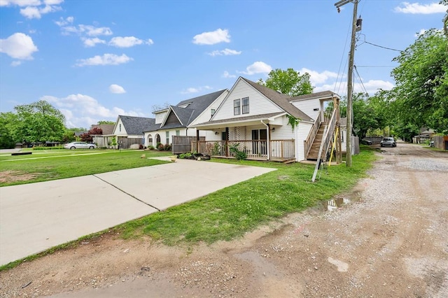 view of front of home with driveway, covered porch, and a front yard