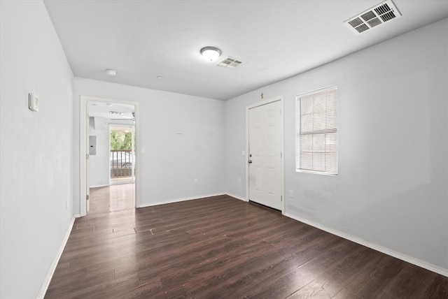 unfurnished room with baseboards, visible vents, and dark wood-style flooring