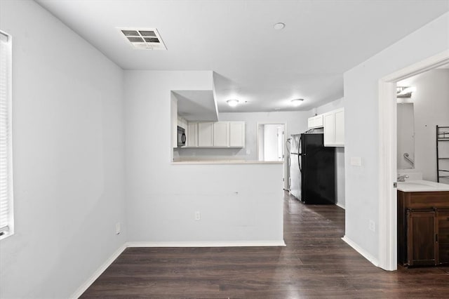 kitchen featuring white cabinetry, visible vents, light countertops, black appliances, and dark wood-type flooring