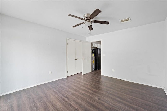 unfurnished room with visible vents, a ceiling fan, dark wood-style floors, and baseboards