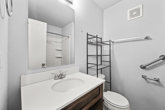 bathroom featuring toilet, visible vents, walk in shower, and vanity