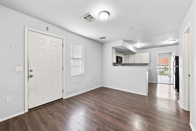 unfurnished living room featuring visible vents, baseboards, and dark wood-type flooring