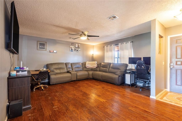 living area with a ceiling fan, visible vents, wood finished floors, and a textured ceiling