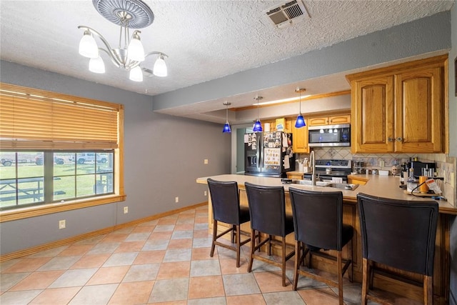 kitchen featuring tasteful backsplash, a breakfast bar, brown cabinetry, stainless steel appliances, and a peninsula