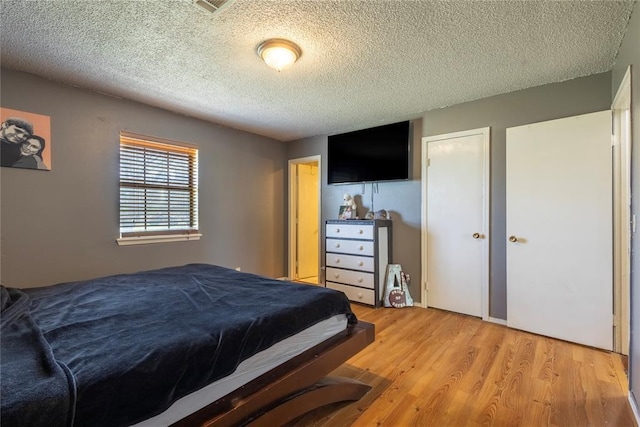 bedroom featuring a textured ceiling, a closet, and light wood-style flooring