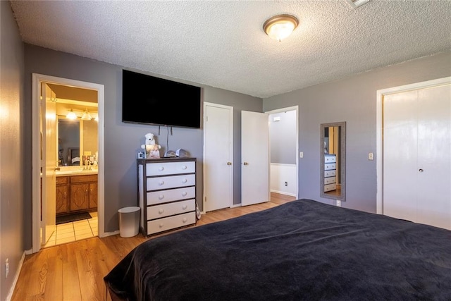 bedroom with wood finished floors, connected bathroom, a closet, baseboards, and a textured ceiling