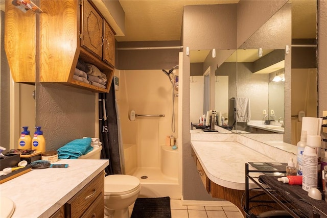 full bath featuring a shower stall, vanity, toilet, a textured wall, and tile patterned flooring