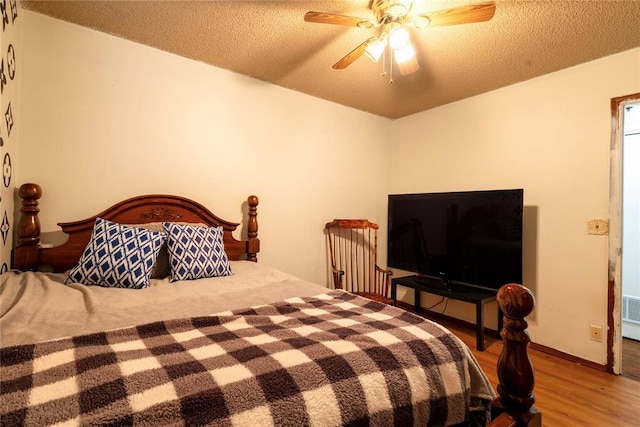 bedroom featuring a textured ceiling, a ceiling fan, wood finished floors, and baseboards