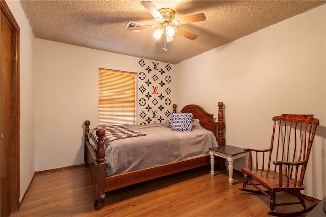 bedroom featuring a textured ceiling, visible vents, wood finished floors, and baseboards