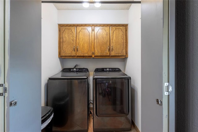 clothes washing area featuring washer and dryer, cabinet space, and a textured ceiling