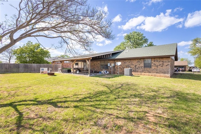 back of property with a fenced backyard, a yard, brick siding, a patio, and cooling unit