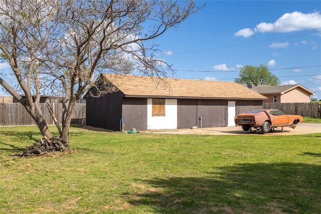 rear view of house with fence, an outdoor structure, and a lawn