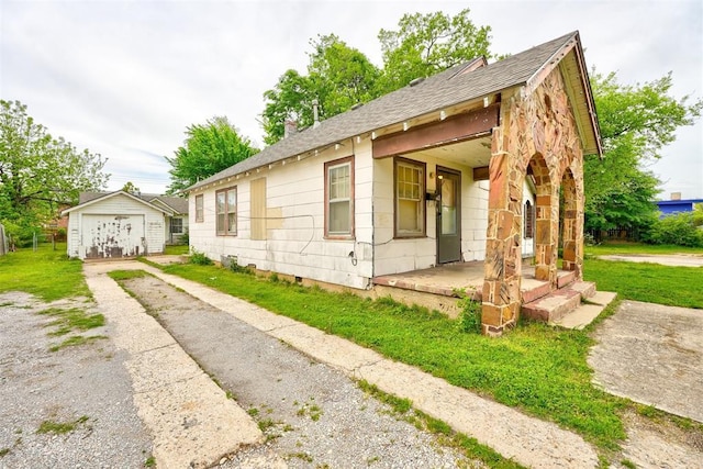 view of side of home with crawl space, a shingled roof, an outbuilding, covered porch, and driveway