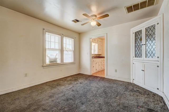 spare room with visible vents, a ceiling fan, baseboards, and light carpet
