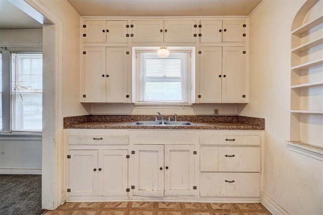 kitchen with a wealth of natural light, dark countertops, open shelves, and a sink