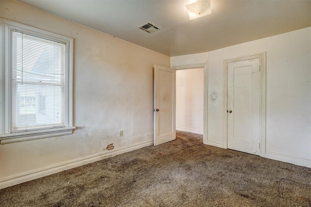 empty room with plenty of natural light, carpet flooring, baseboards, and visible vents