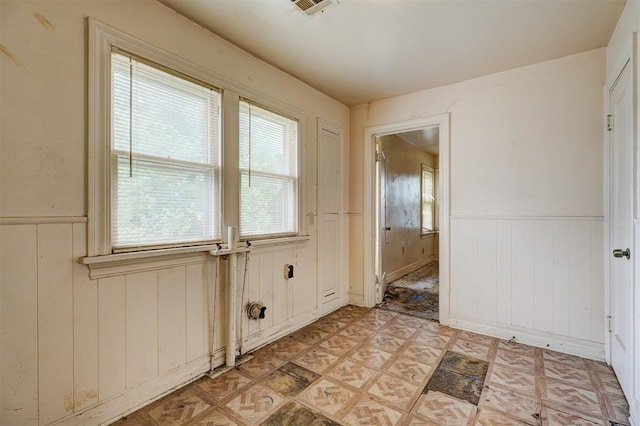 interior space featuring light floors, visible vents, and wainscoting