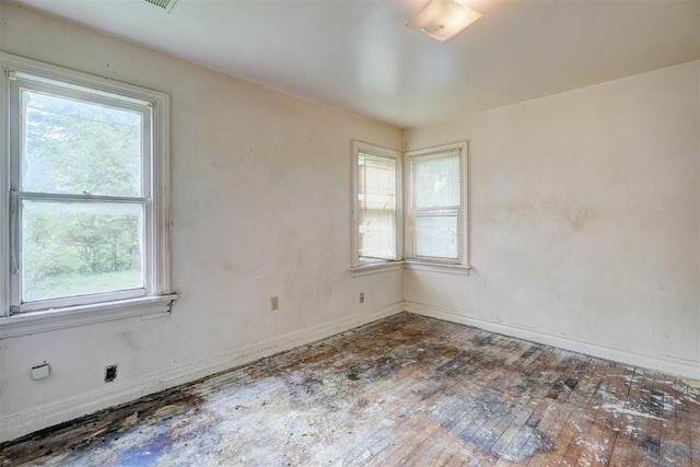 unfurnished room with a healthy amount of sunlight, wood-type flooring, and baseboards