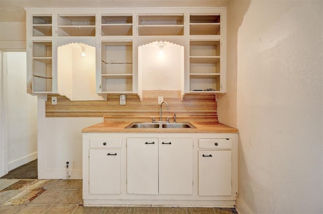 kitchen featuring white cabinetry, open shelves, light countertops, and a sink