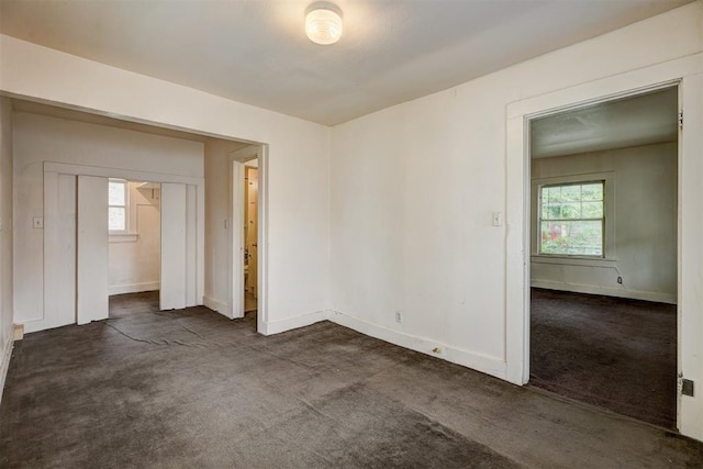 empty room with dark carpet and baseboards