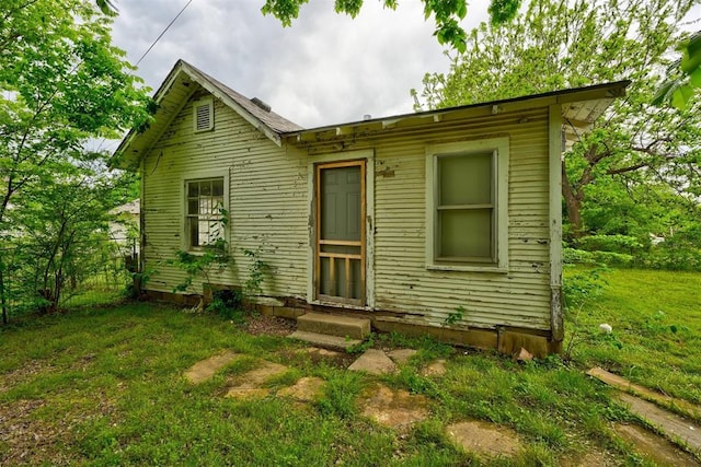 back of house featuring a lawn, fence, and entry steps