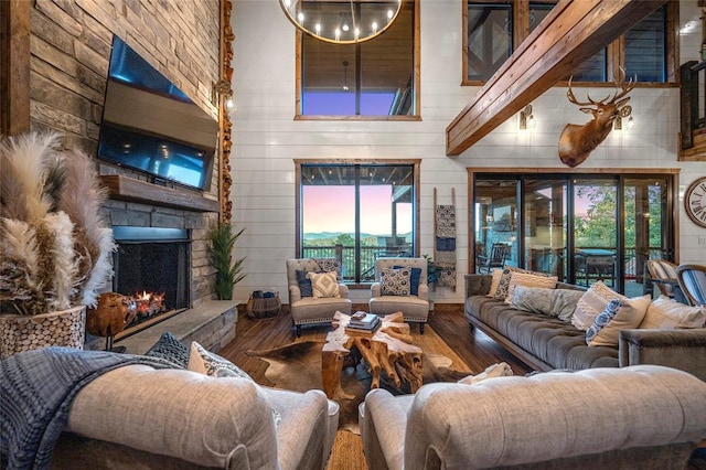 1329 Lake Ridge Ln, Broken Bow, OK 74728 - living room featuring hardwood / wood-style flooring, a stone fireplace, a high ceiling, and wood walls