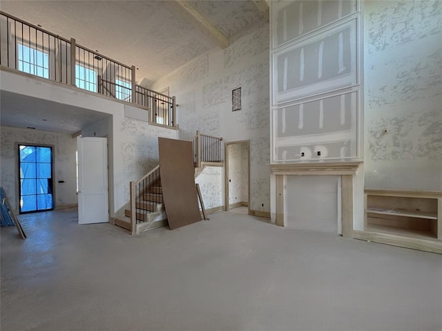 unfurnished living room with stairs, a high ceiling, and a wealth of natural light