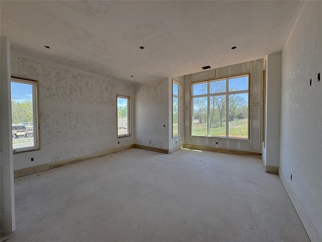 unfurnished room featuring baseboards and unfinished concrete flooring