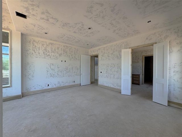 unfurnished bedroom with concrete flooring and wallpapered walls