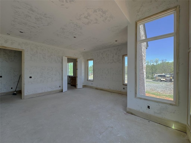 interior space with baseboards, plenty of natural light, and unfinished concrete floors