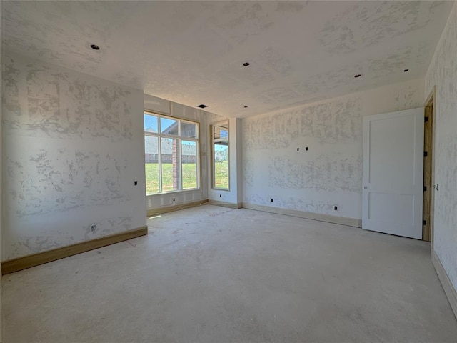 unfurnished room with baseboards and unfinished concrete floors