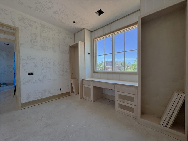 unfurnished office featuring unfinished concrete floors and built in study area