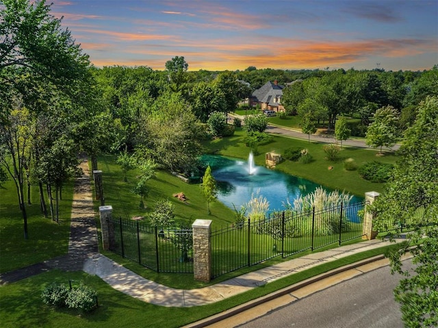 view of home's community featuring a lawn, a water view, and fence